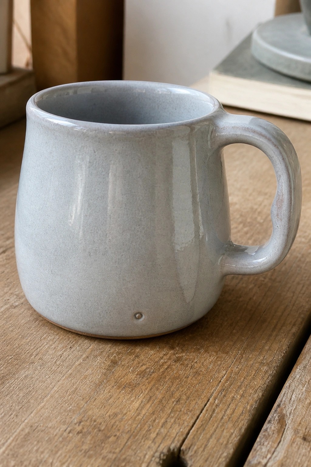 Speckled light gray ceramic mug with handle on wooden table