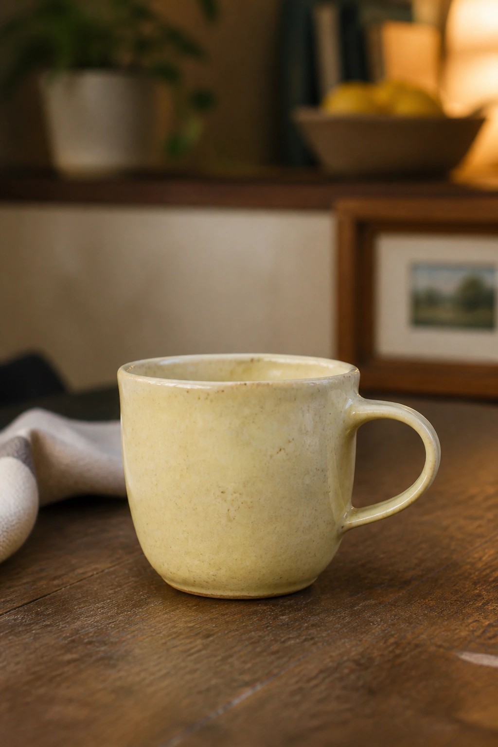 Pale yellow ceramic mug on dark wooden table with blurred background