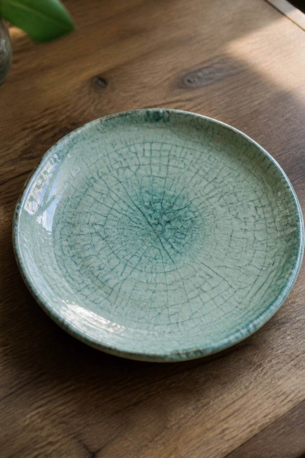 A round ceramic plate with green crackle glaze on a wooden surface.