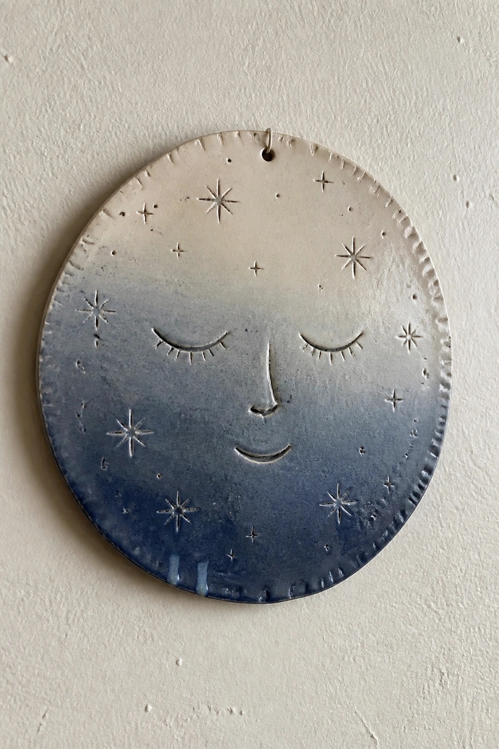 Ceramic moon face plaque with closed eyes, stars, and blue gradient glaze