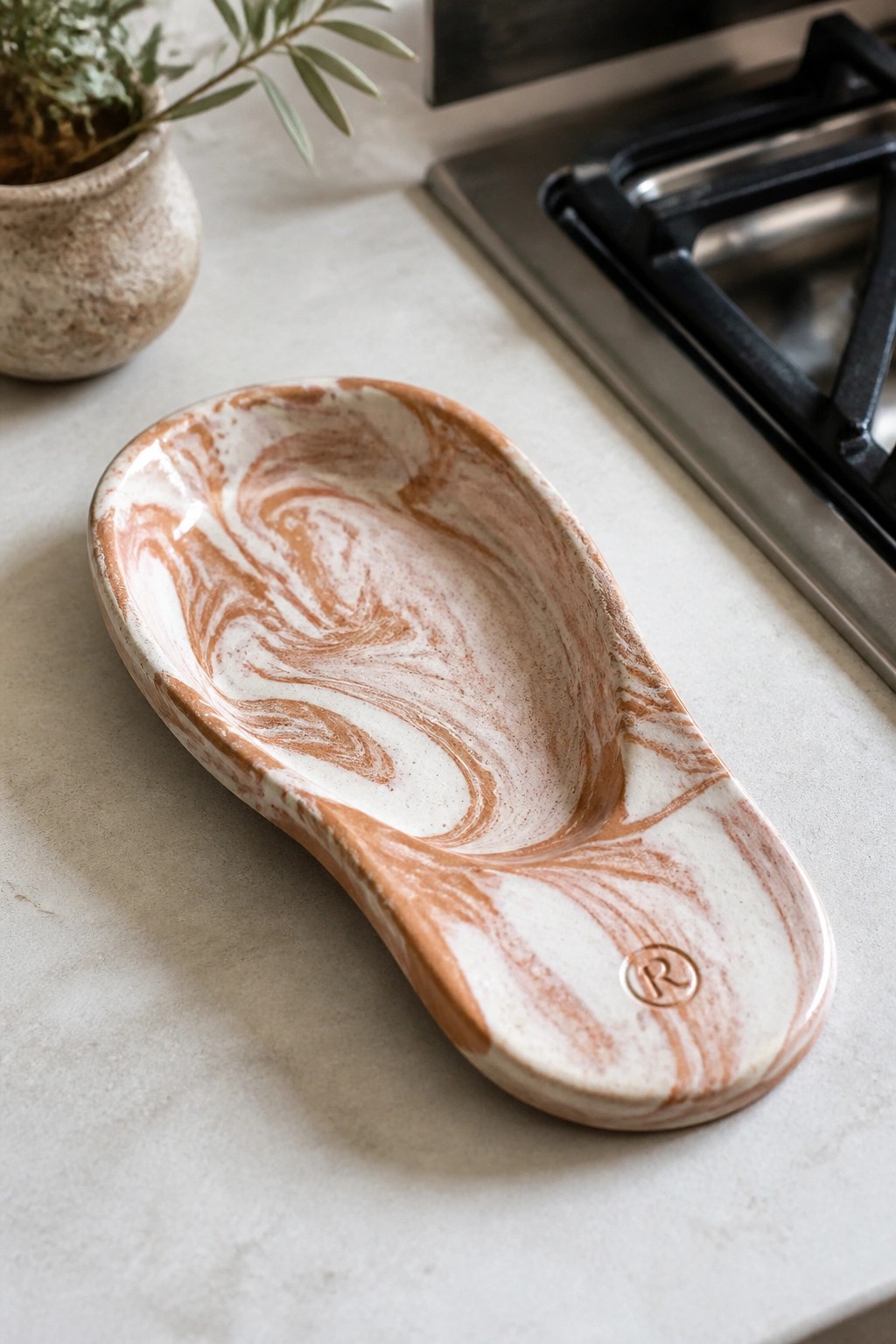 Marbled white and brown ceramic spoon rest on kitchen countertop near stove