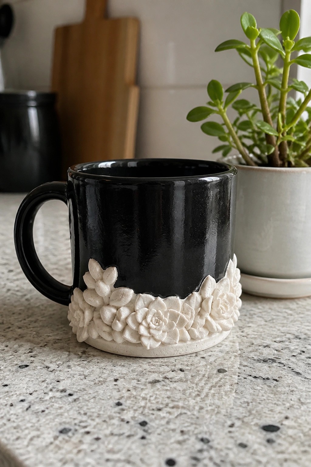 Black mug with white raised succulent designs on speckled countertop