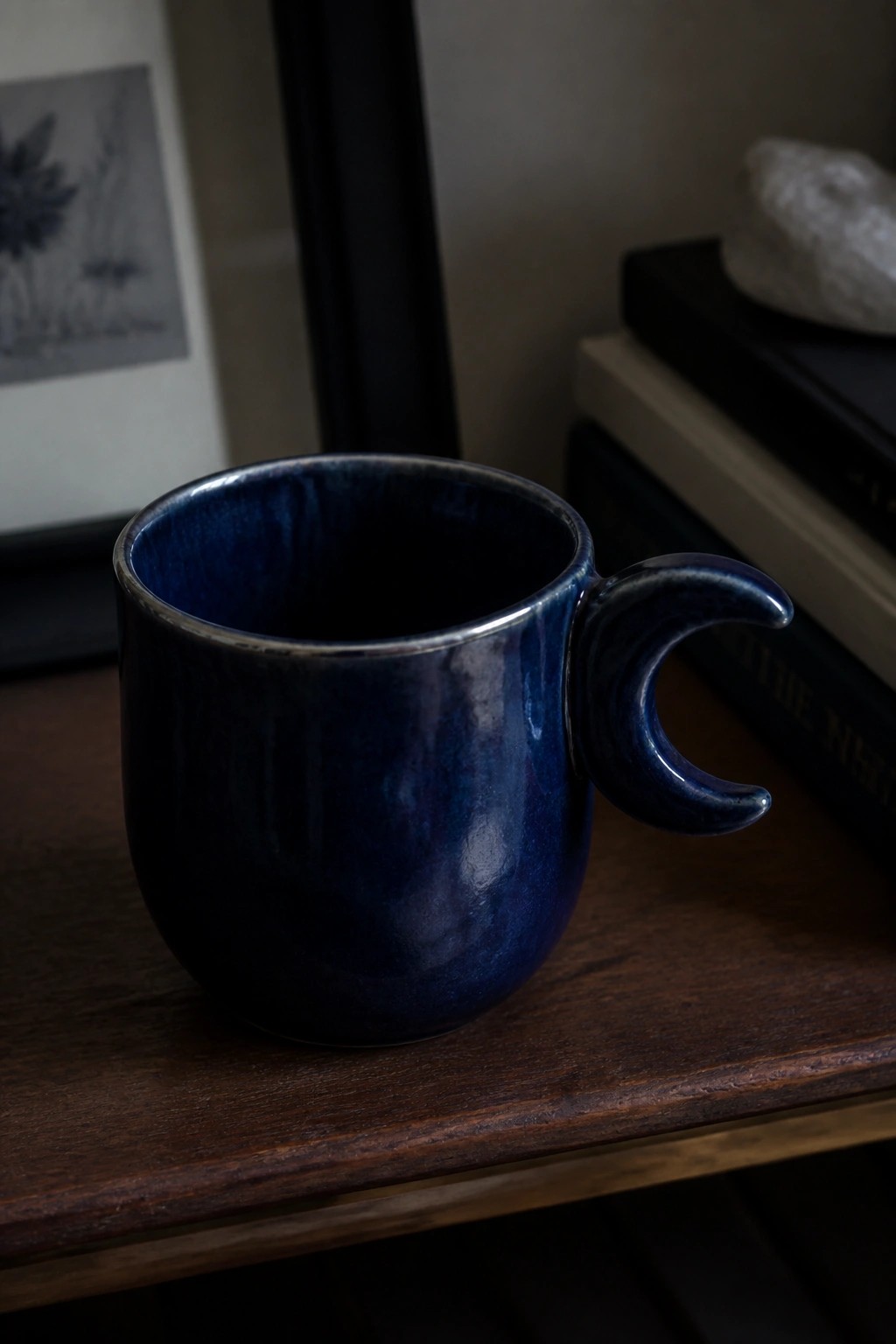 Deep blue ceramic mug with crescent moon handle on wooden table