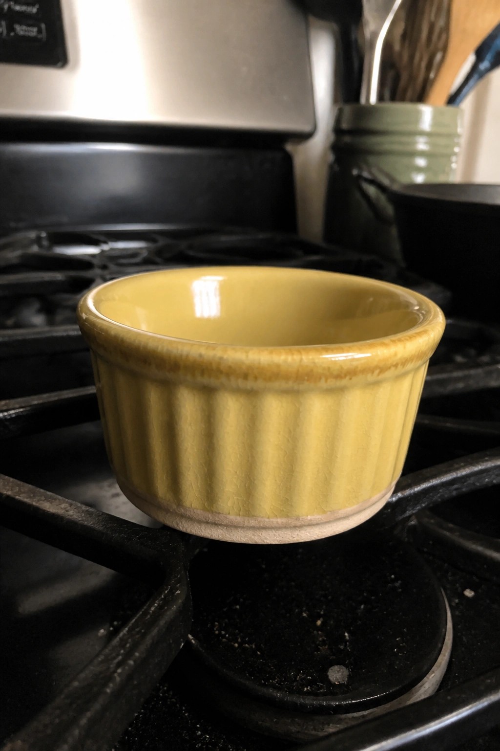 Yellow ribbed ceramic bowl on black gas stove grates