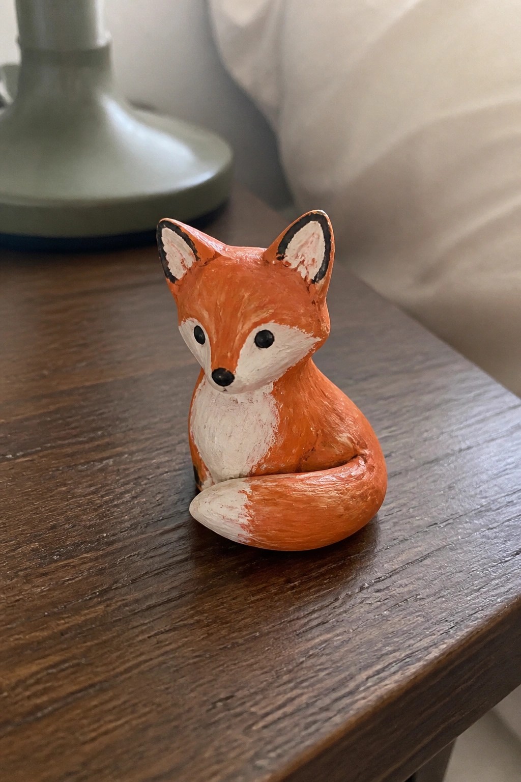 Orange wooden fox figurine with white accents on dark wood table