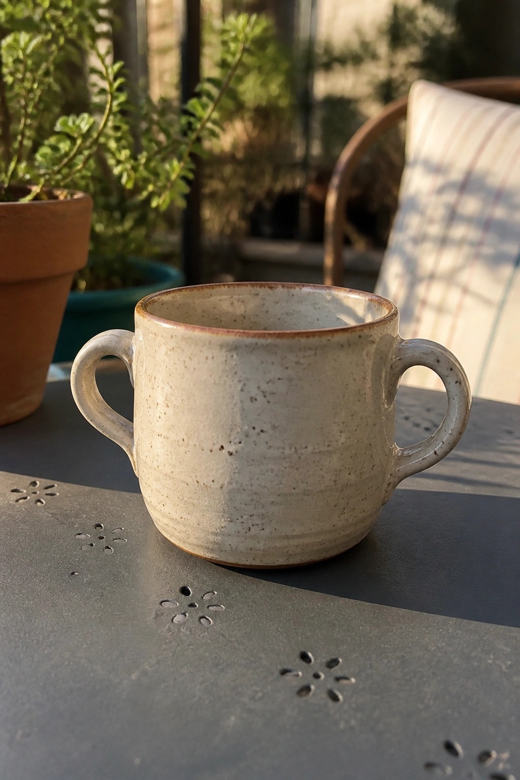 Speckled beige ceramic mug with two handles on dark outdoor table