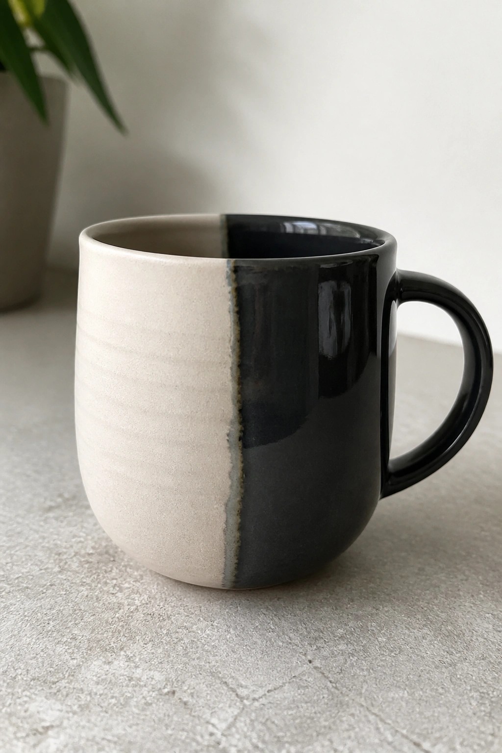 Two-toned ceramic mug split between beige and glossy black glaze