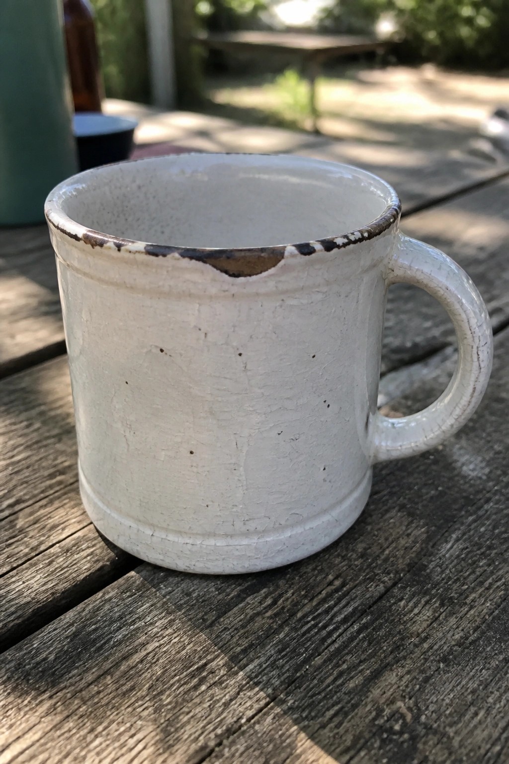 White ceramic mug with crackled glaze and chipped rim on wooden table
