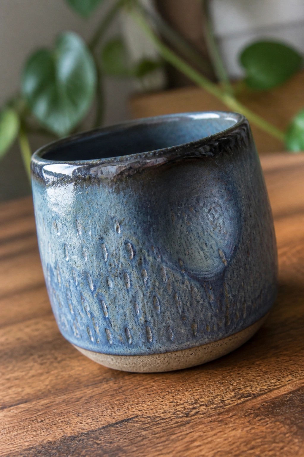 Blue speckled ceramic cup with textured glaze on wooden table.
