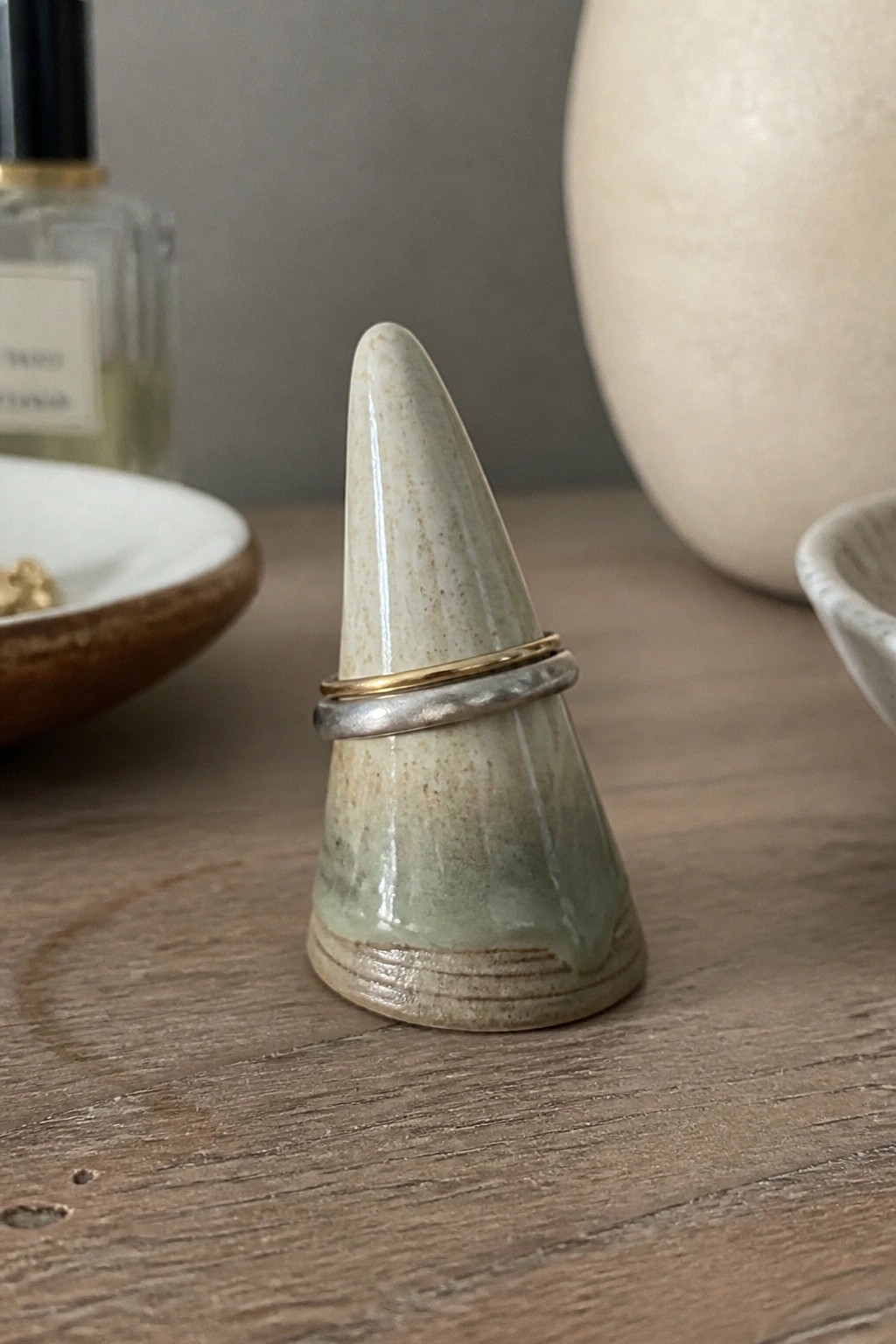 Ceramic cone ring holder with gold and silver bands on wood