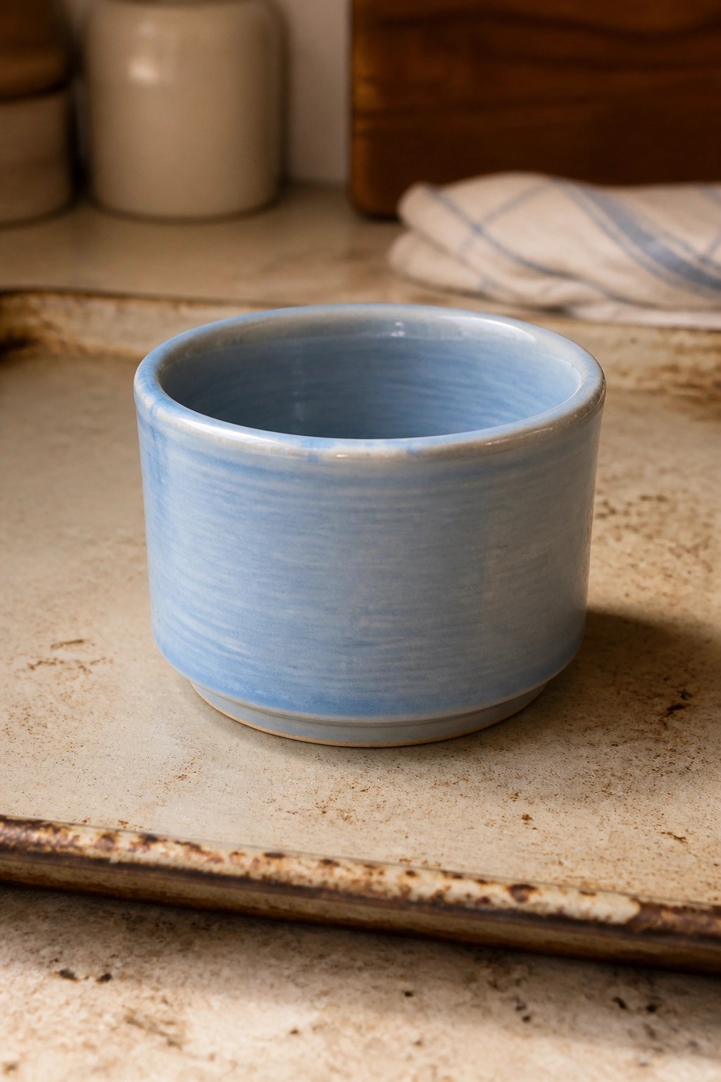 Light blue ceramic bowl on a worn beige kitchen countertop with blurred background items