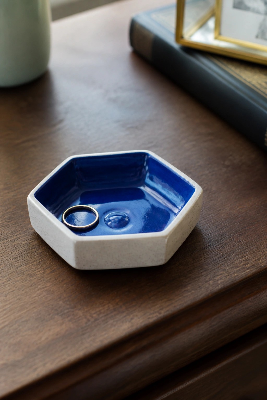 Hexagonal blue ceramic dish with gold ring and water droplet on wood.