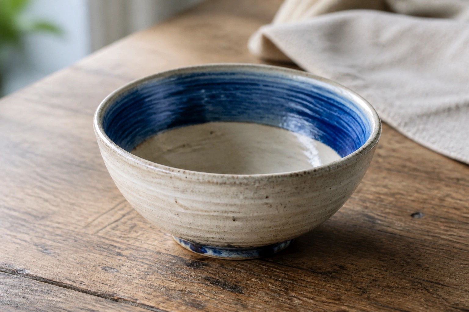 Blue and white ceramic bowl on wooden table with white cloth nearby
