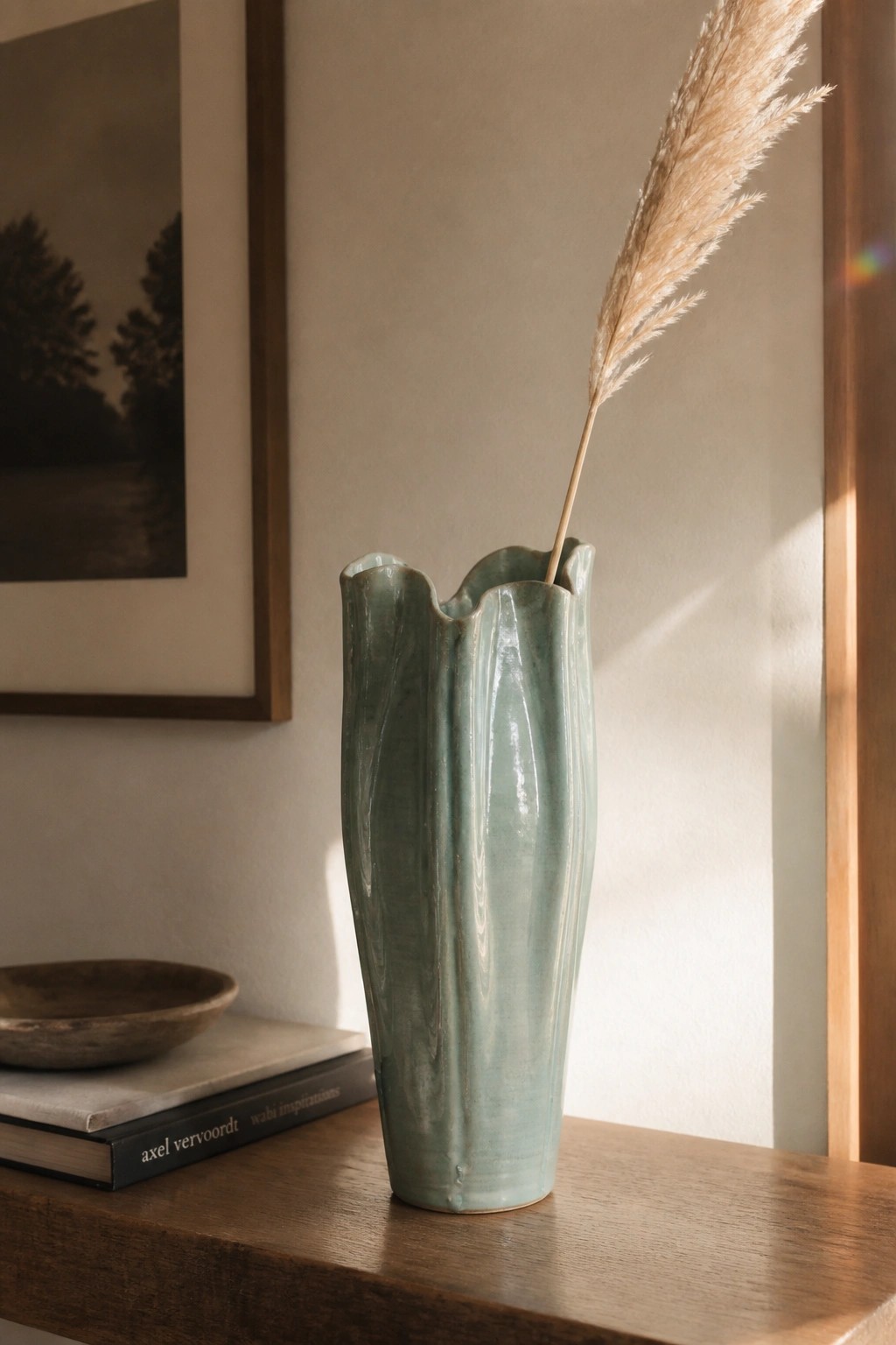 Sage green ridged vase with dried pampas grass on wooden table near books
