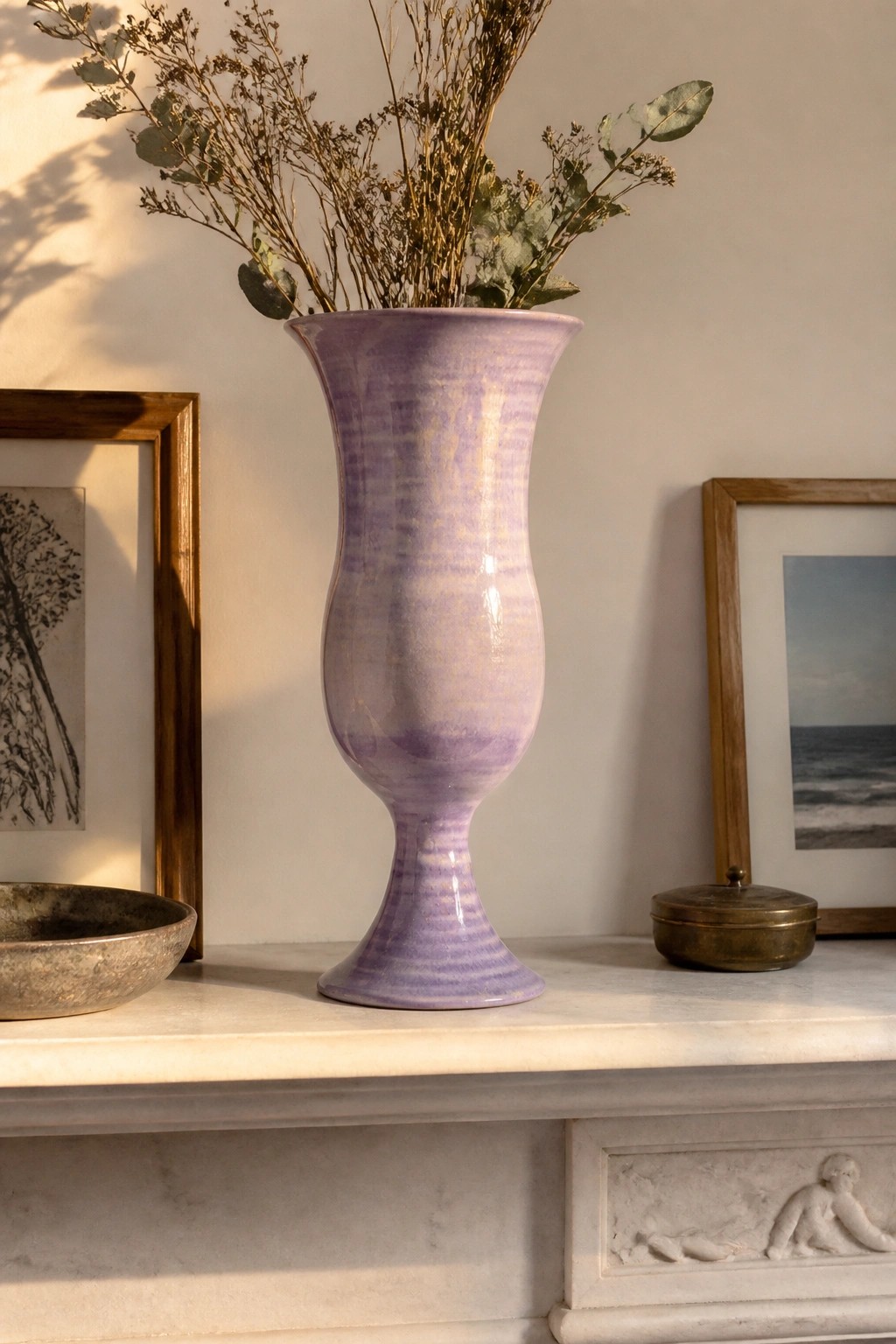 Striped purple ceramic vase with dried branches on marble mantelpiece