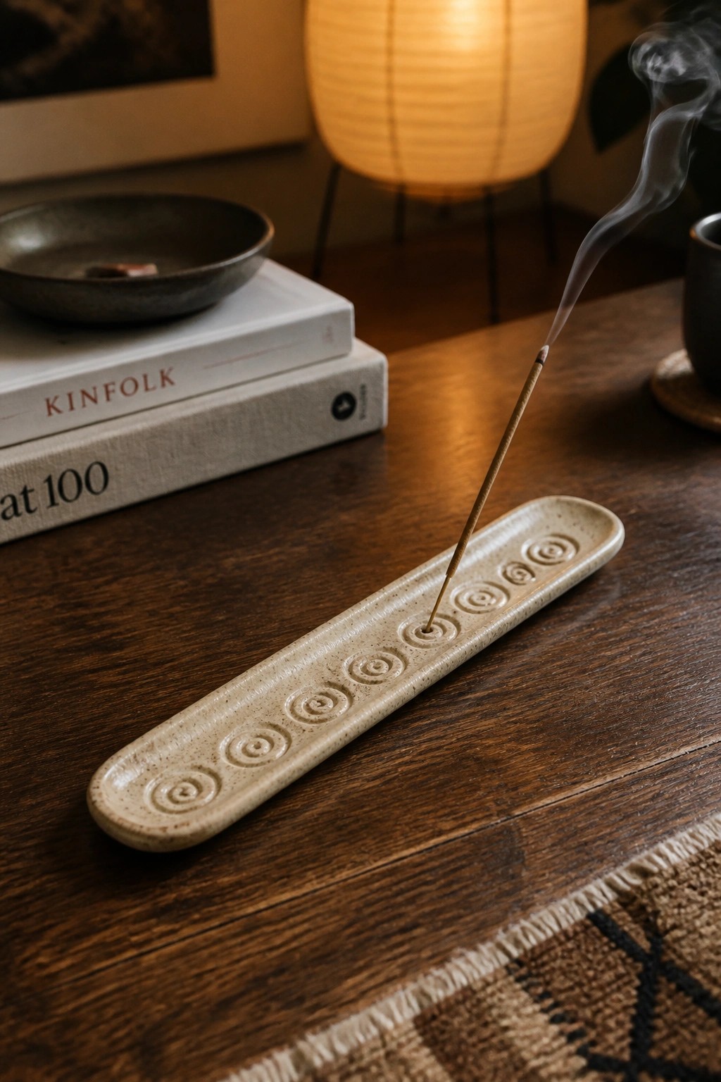 Burning incense stick in beige ceramic holder with spirals on wooden table
