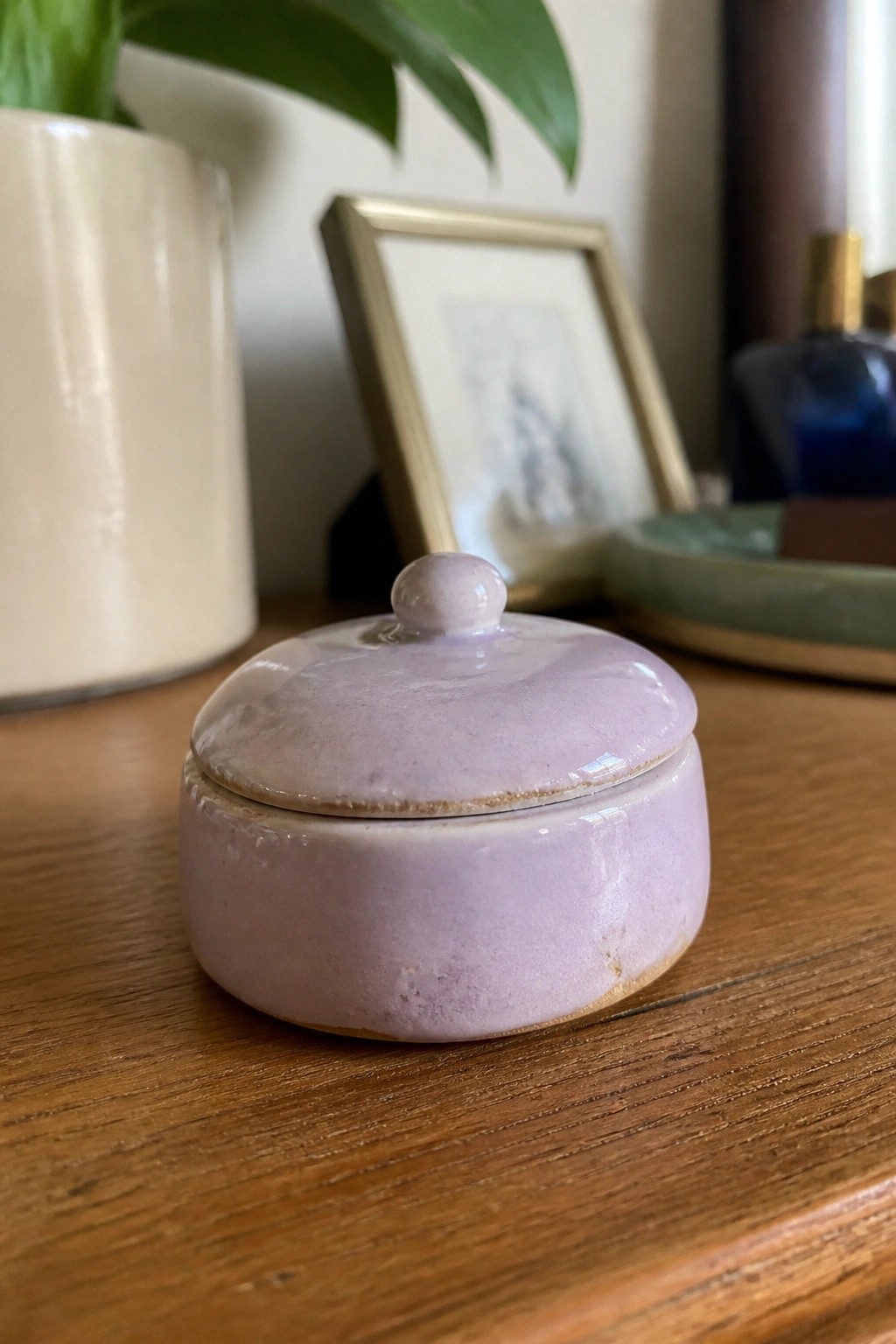 Small light purple ceramic jar with lid on wooden table