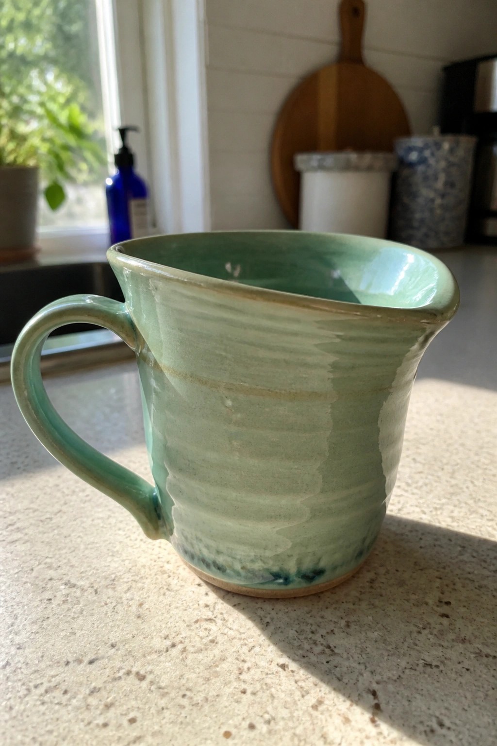 Green ceramic mug with handle on sunlit kitchen countertop