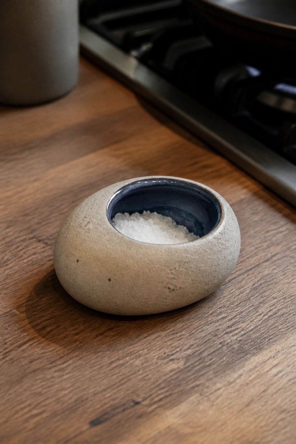Speckled beige ceramic bowl with blue interior filled with salt on wooden counter