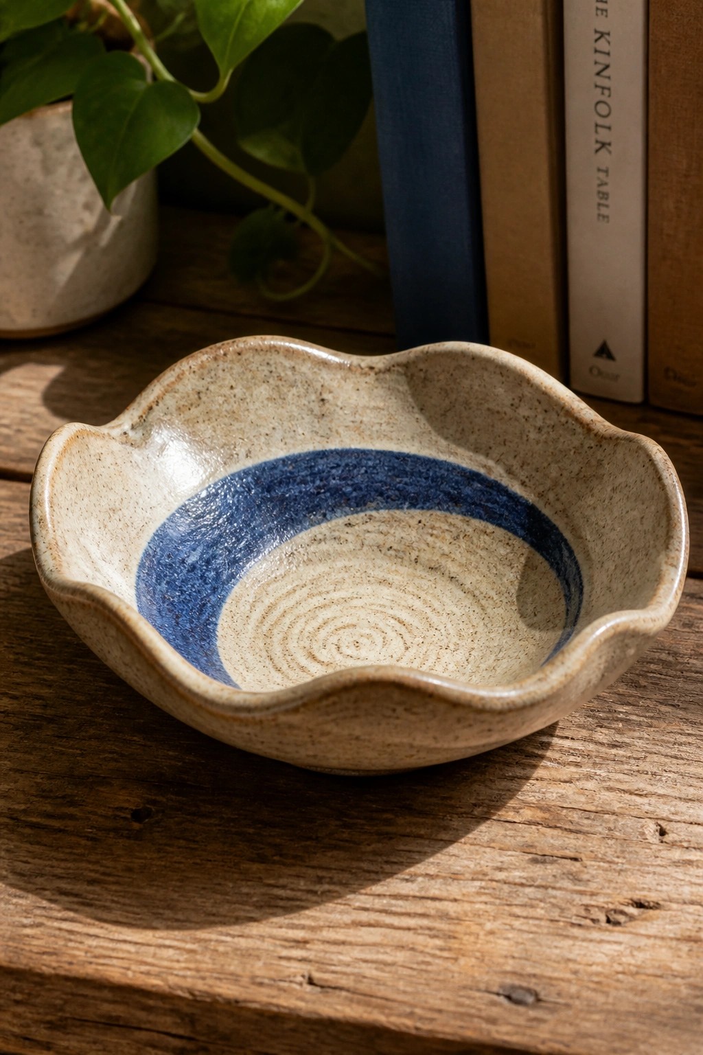 Speckled ceramic bowl with blue spiral glaze and scalloped rim on wood