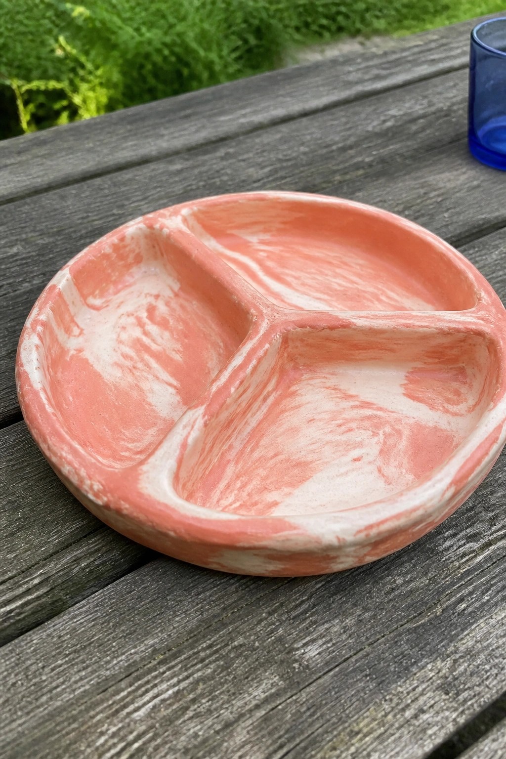 Marbled coral pink ceramic divided plate on weathered wooden table