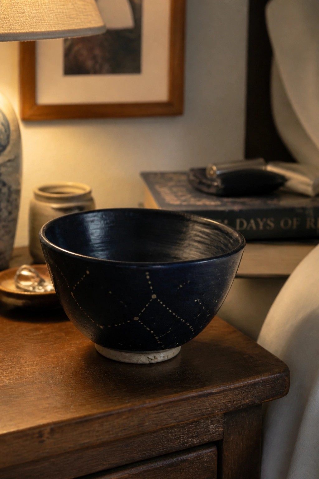 Deep blue bowl with white constellation dots on rustic wooden nightstand.