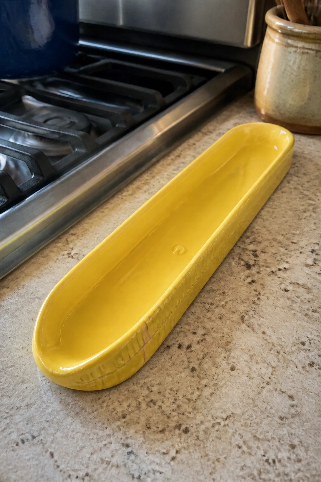 Yellow oblong ceramic dish on speckled kitchen countertop near stove