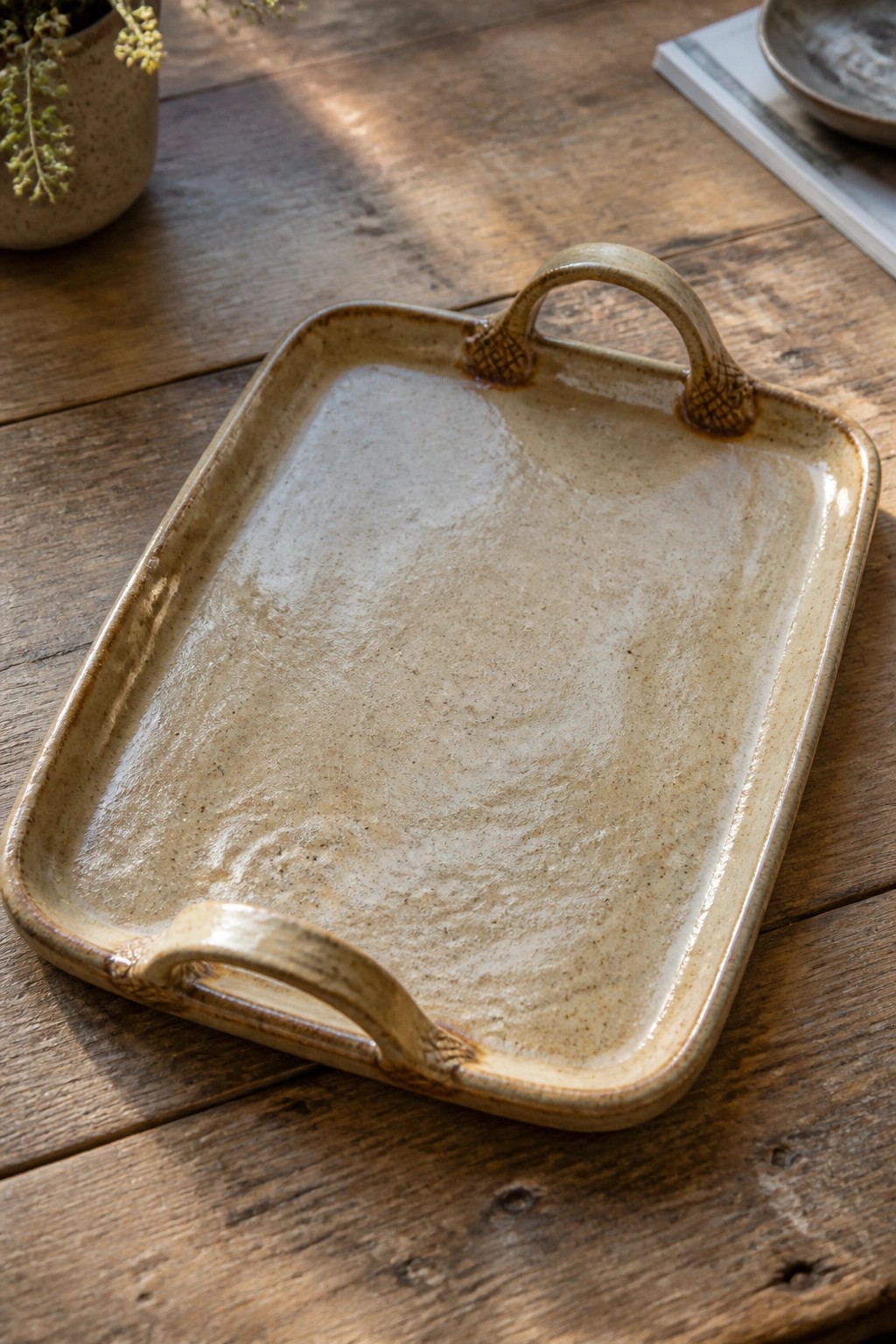 Rectangular beige ceramic tray with handles on rustic wooden table