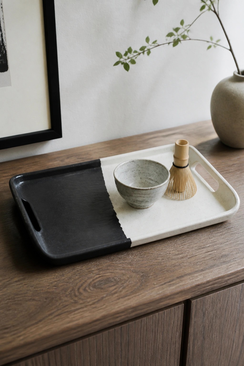 Black and white tray with speckled bowl and bamboo whisk on wooden table