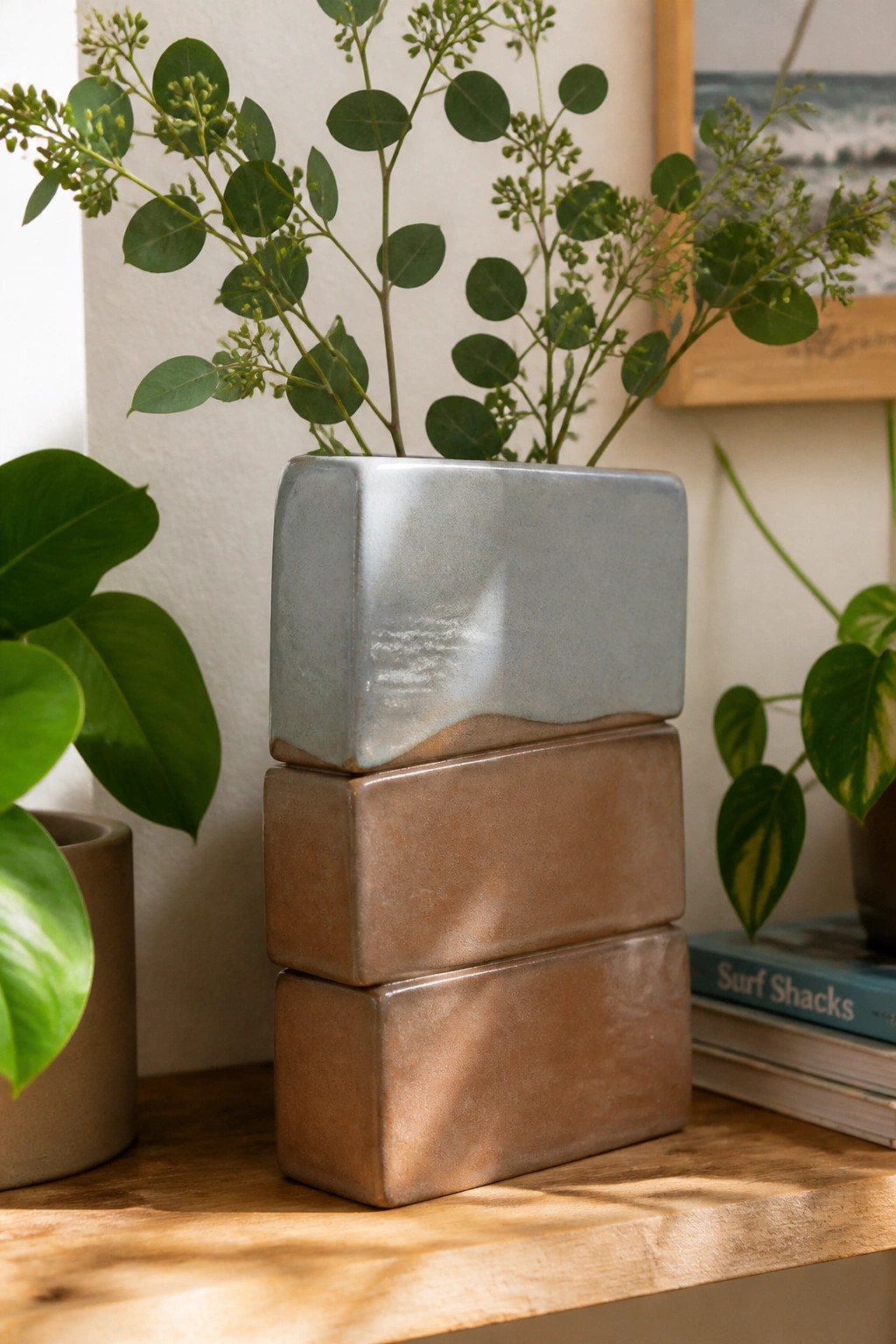 Stacked blue and brown ceramic vases with green plants on wooden table