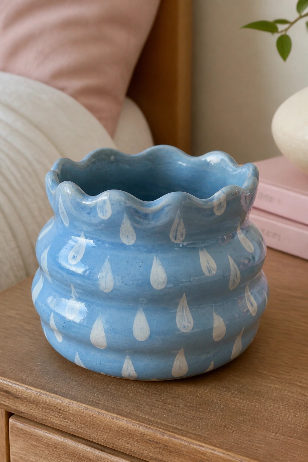 Blue ceramic pot with scalloped rim and white teardrop patterns on wooden table.