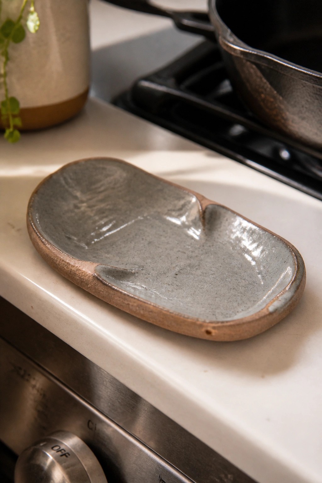 Gray ceramic dish with brown rim on white kitchen counter near stove