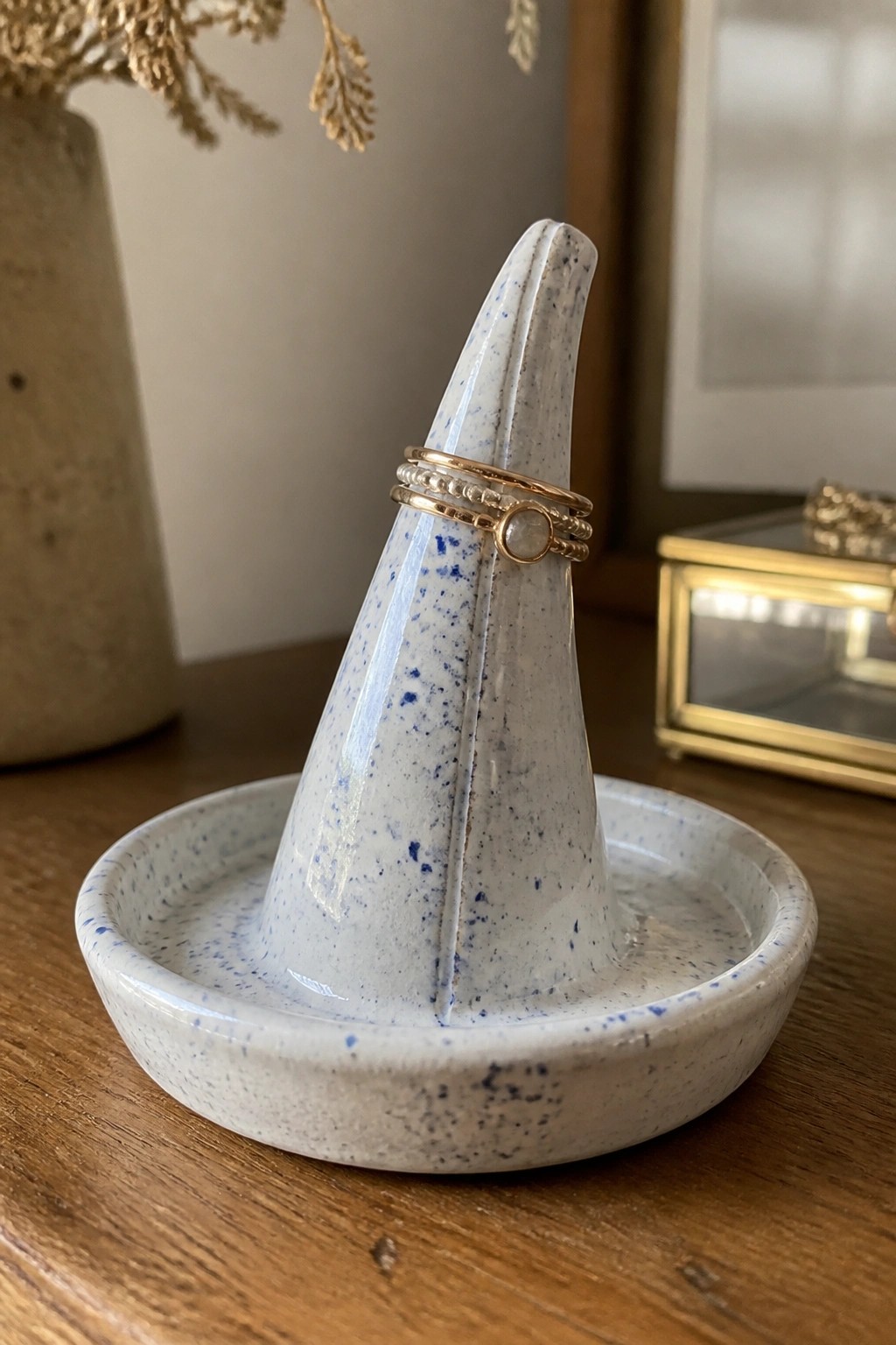 Speckled blue and white ceramic ring holder with gold rings on wooden table