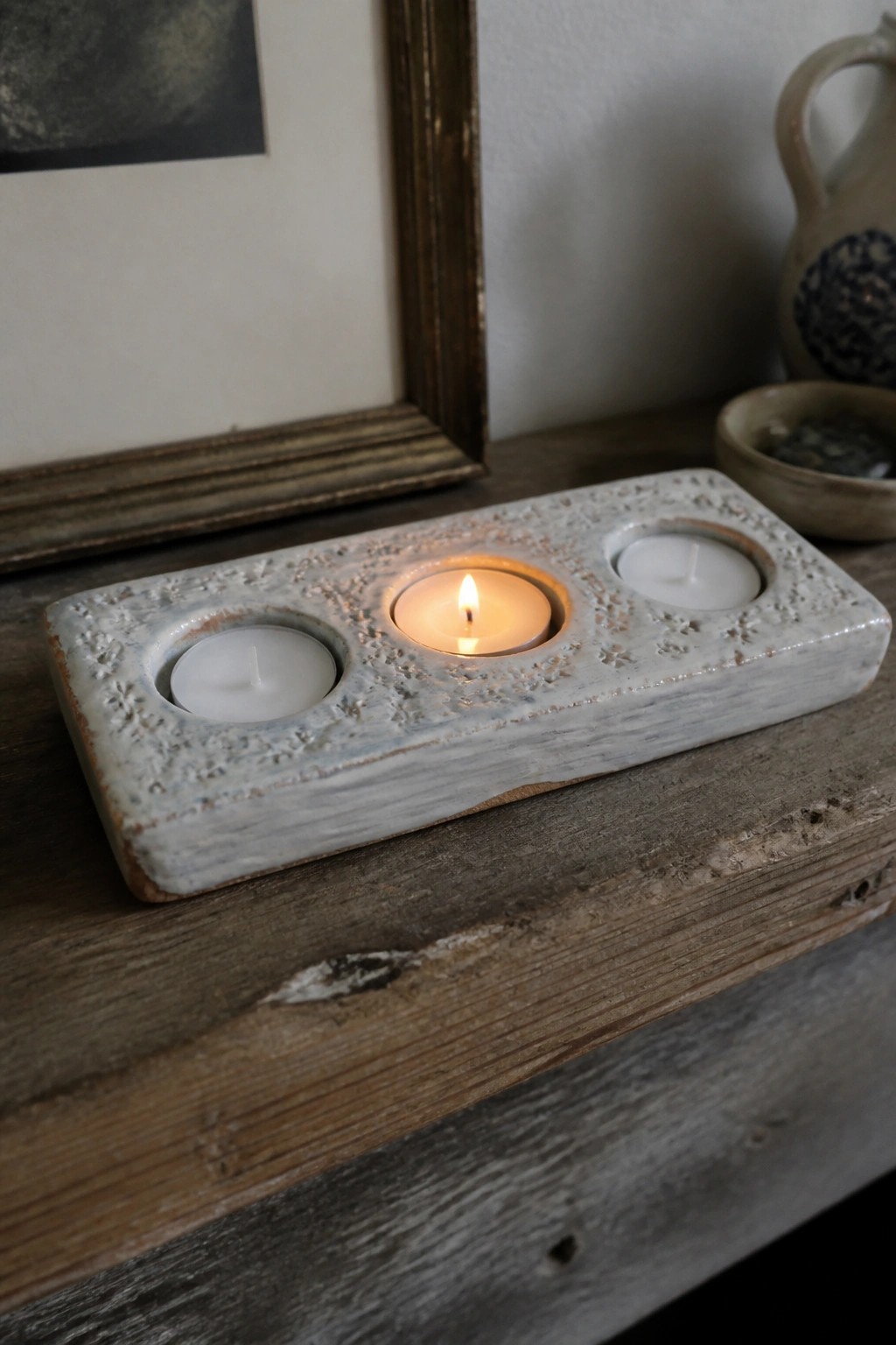 Rustic blue ceramic holder with snowflake patterns holding three tea lights on wood