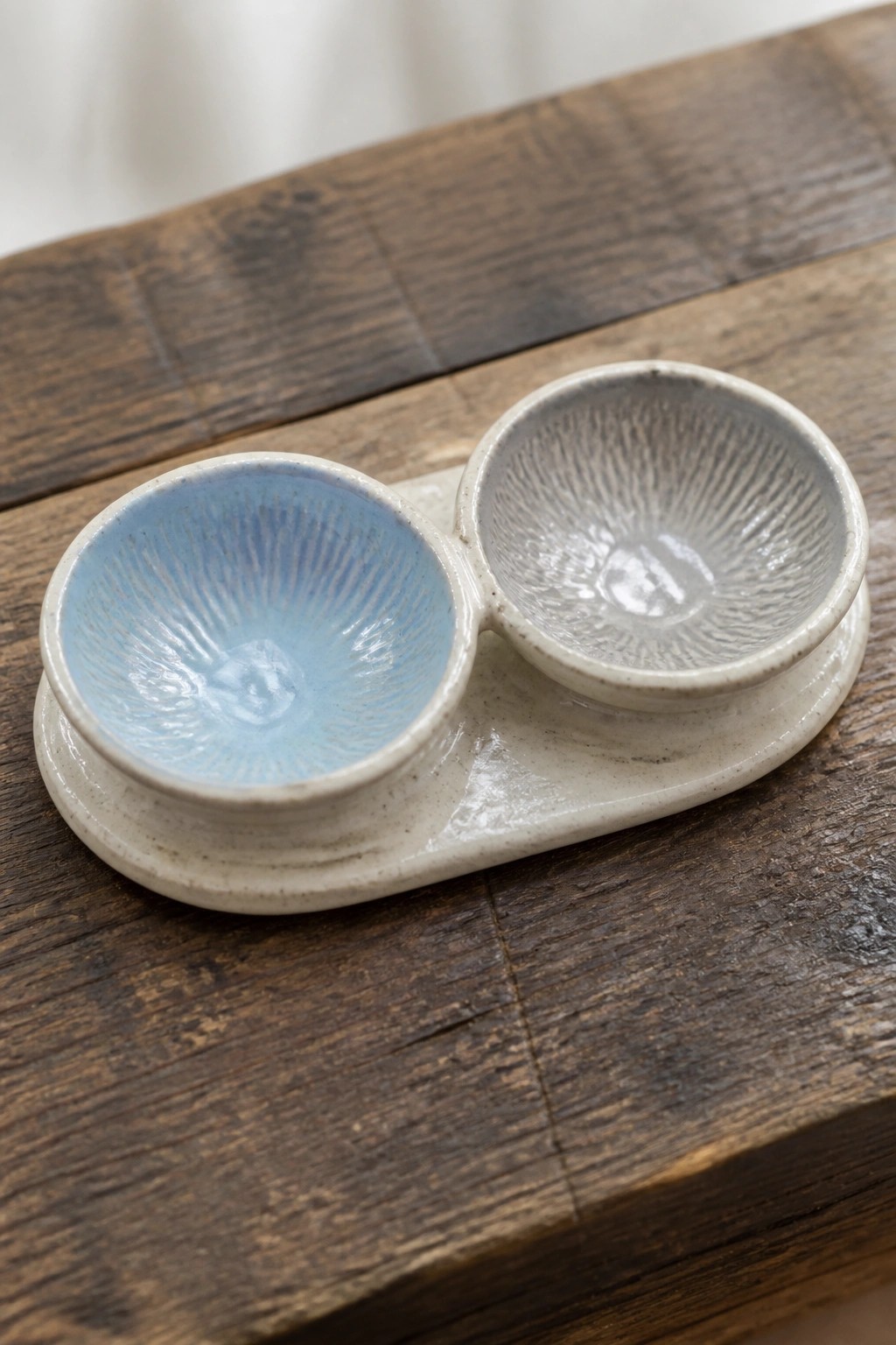 Two ceramic bowls with blue and gray sunburst glazes on rustic wood