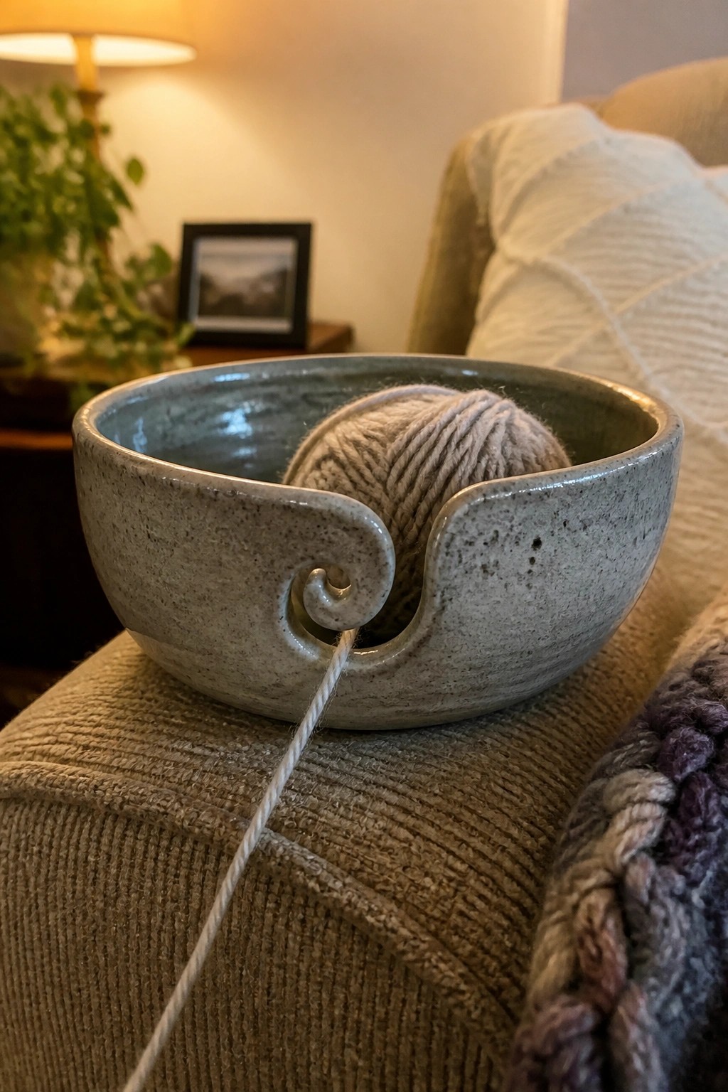 Ceramic yarn bowl with beige yarn on textured brown couch arm