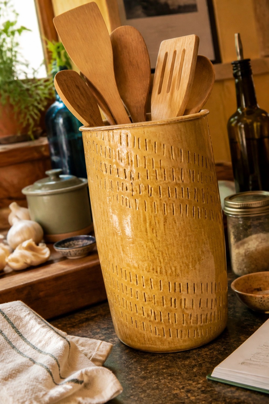 Yellow ceramic crock filled with wooden spatulas and spoons on kitchen counter
