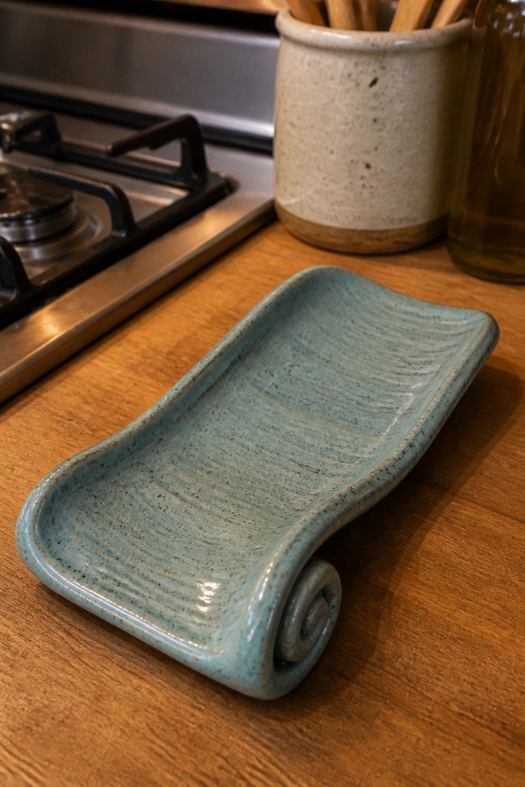 Light blue ceramic tray with spiral edge on wooden kitchen counter near stove