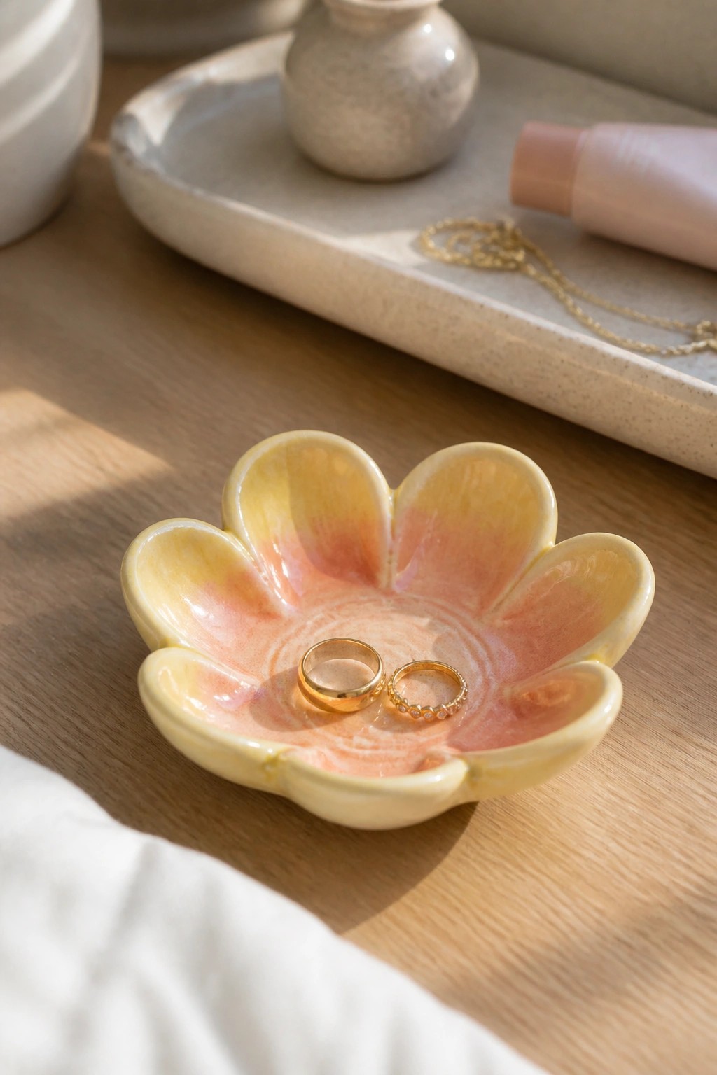 Colorful flower-shaped ceramic bowl holding two gold rings on wooden table
