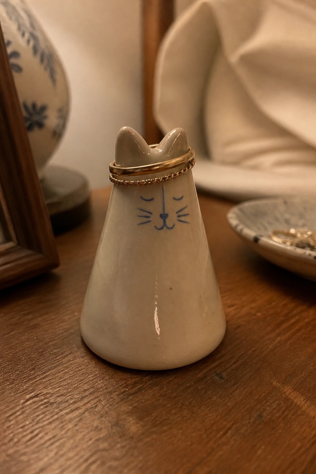 White ceramic cat figurine with gold rings on wooden table.