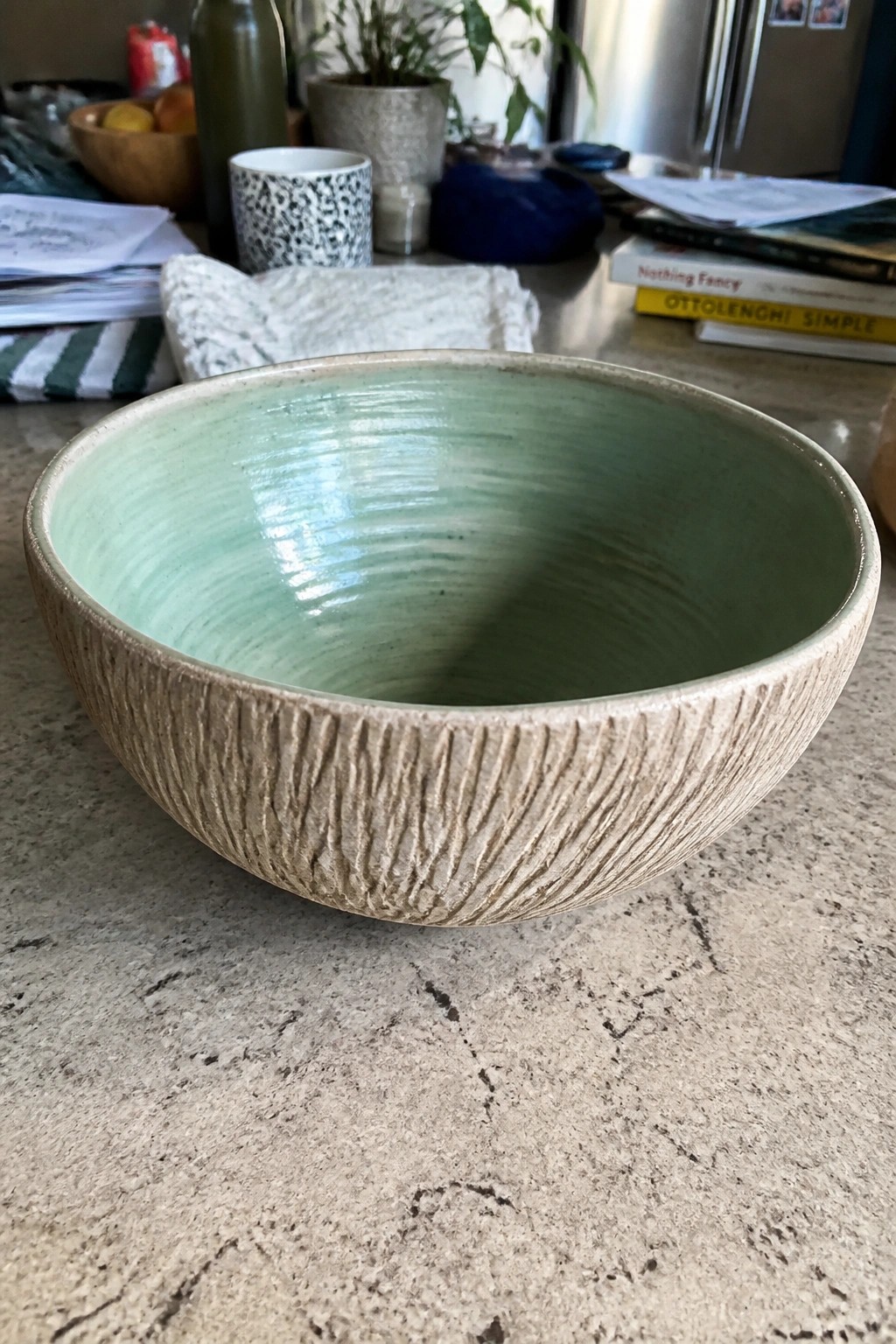 Green ceramic bowl with textured beige exterior on kitchen countertop