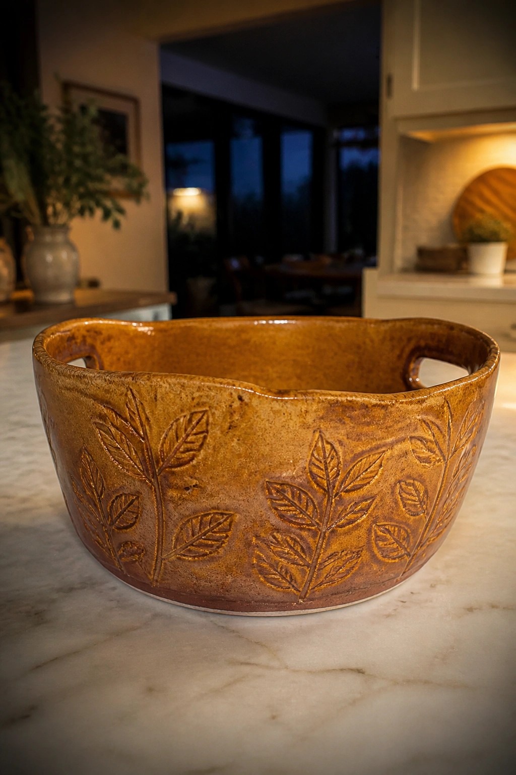 Brown ceramic bowl with embossed leaf patterns on marble kitchen counter