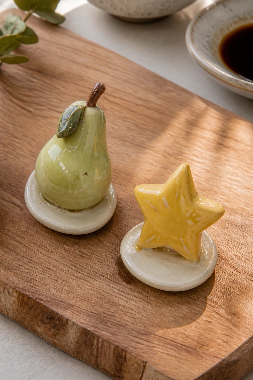 Green pear and yellow star ceramic figurines on wooden cutting board