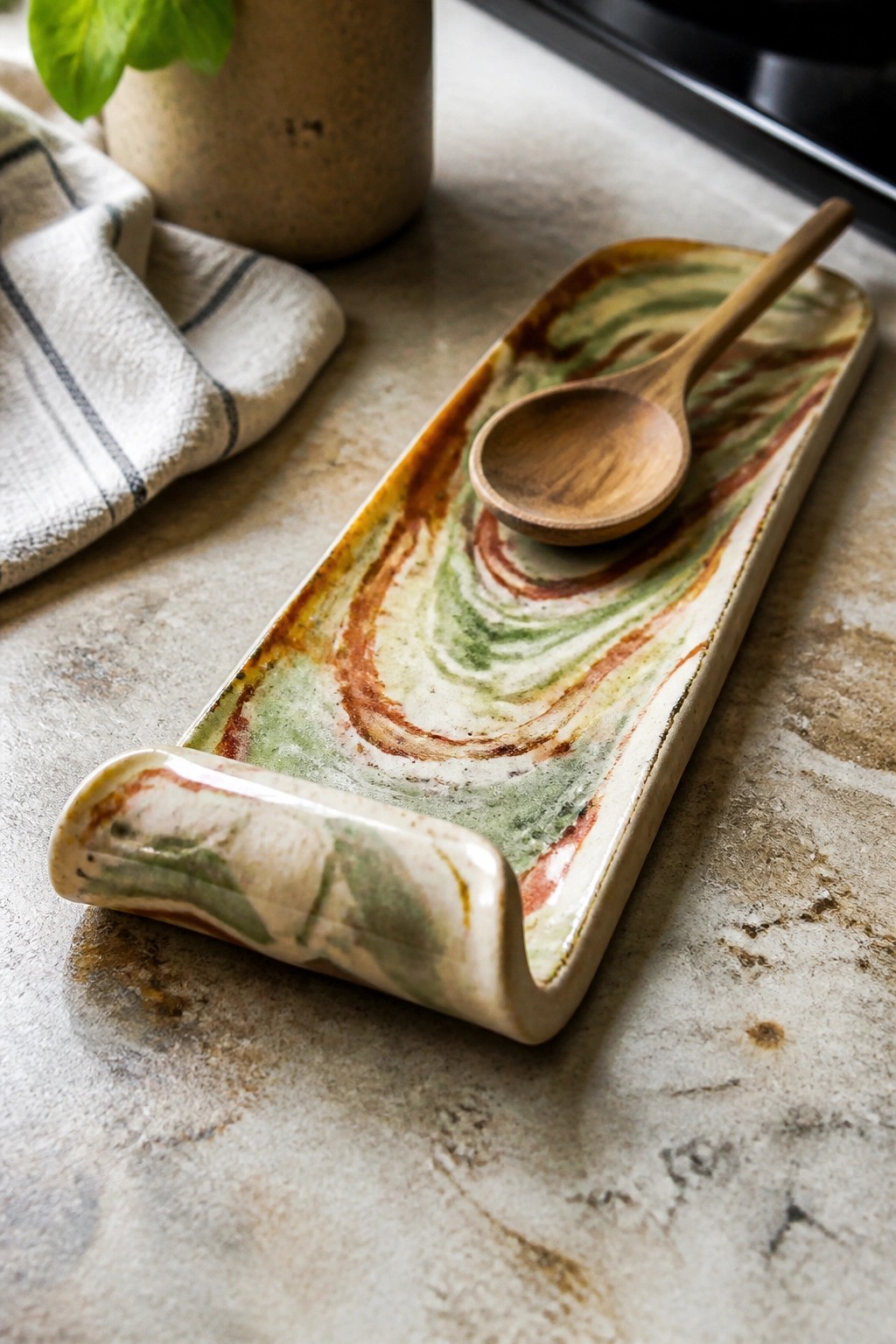 Marbled ceramic tray with wooden spoon on stone kitchen countertop