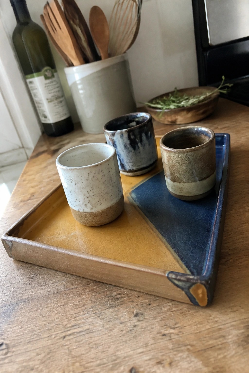 Three ceramic cups on a yellow and blue diagonally divided pottery tray