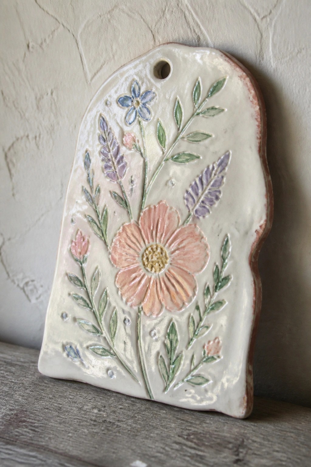 Ceramic plaque with pink daisy, blue flower, lavender sprigs, and green leaves