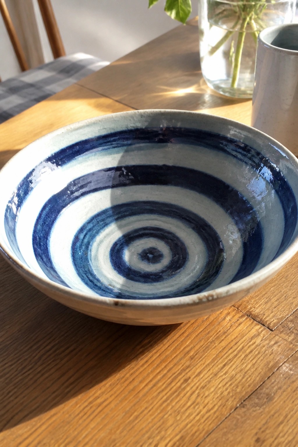 Blue and white concentric ceramic bowl on sunlit wooden table.