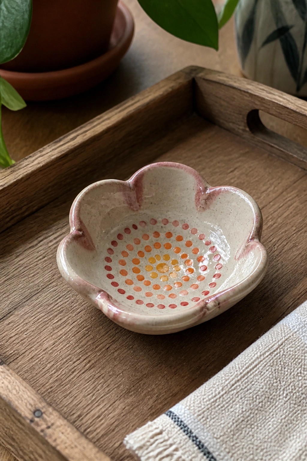 Flower-shaped ceramic bowl with pink rim and orange dot pattern on wooden tray