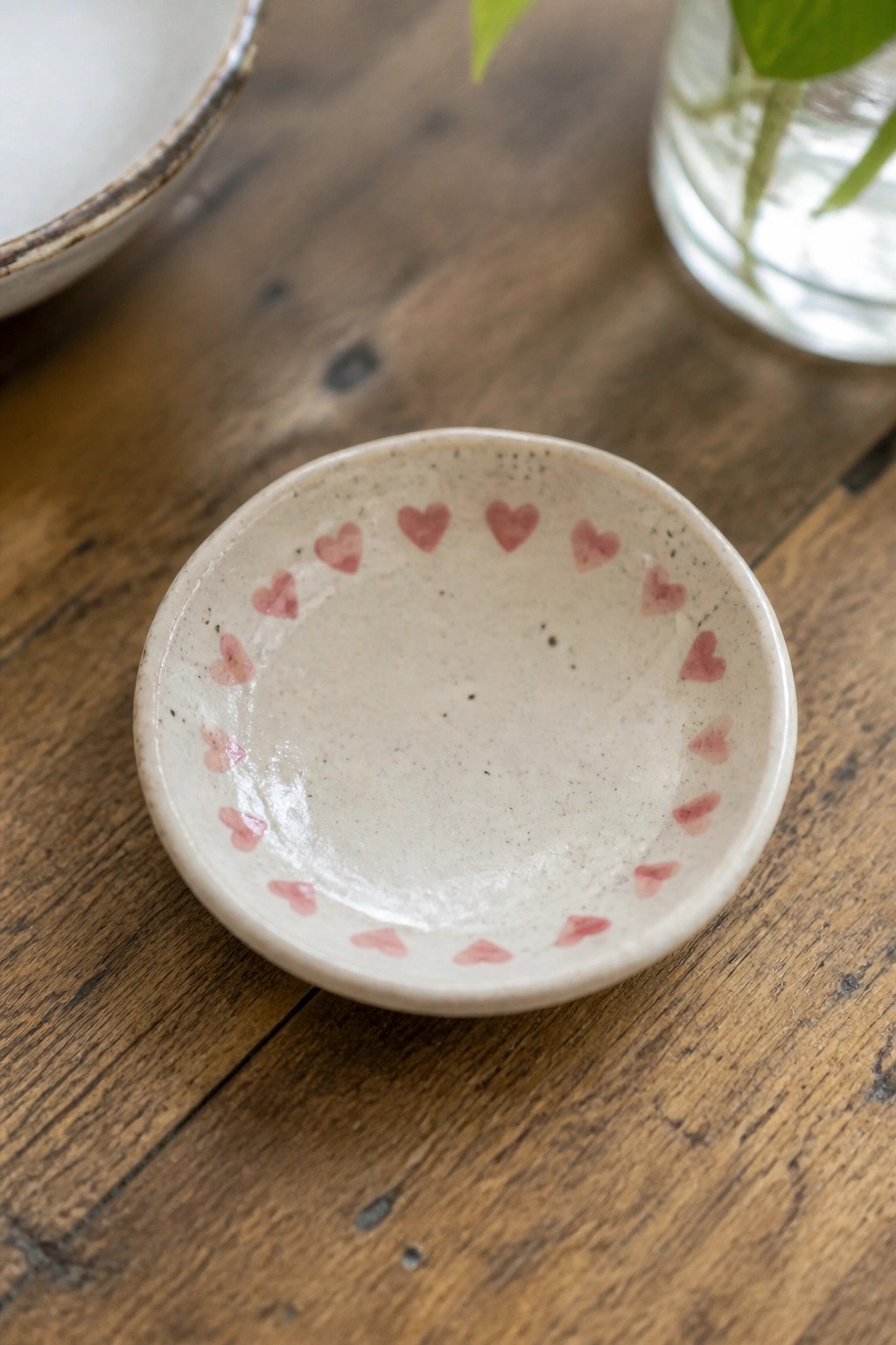 Small speckled ceramic bowl with pink hearts on rustic wooden table