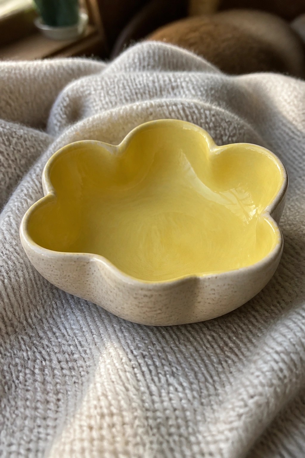 Yellow scalloped ceramic bowl on textured white knitted fabric